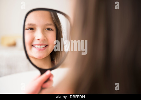 Mixed race girl admiring herself in mirror