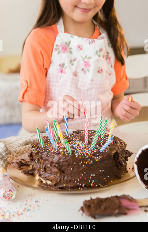 Mixed race girl making birthday cake in kitchen