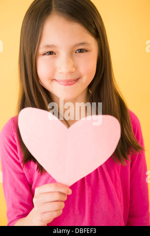 Mixed race girl holding heart Stock Photo