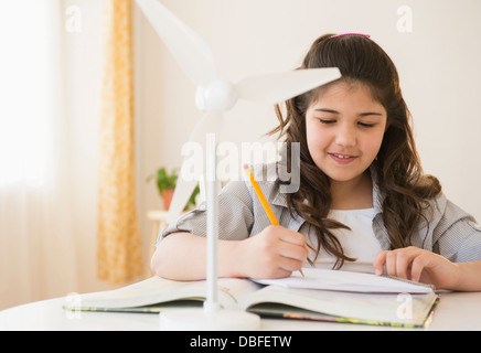 Hispanic girl with model wind turbine doing homework Stock Photo