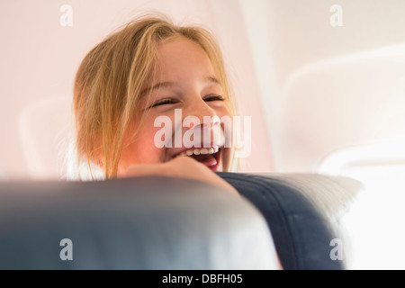 Caucasian girl laughing on airplane Stock Photo