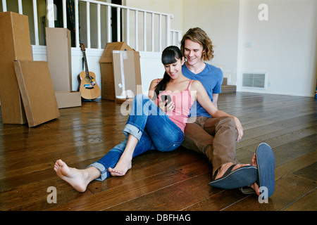 Couple using cell phone in new home Stock Photo