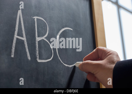 Hispanic teacher writing 'ABC' on chalkboard Stock Photo