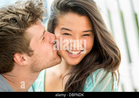 Man kissing girlfriend's cheek outdoors Stock Photo
