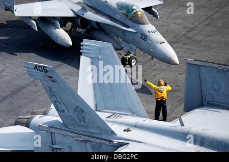 A U.S. Sailor directs an F/A-18C Hornet aircraft assigned to Strike Fighter Squadron (VFA) 37 on the flight deck of the aircraft carrier USS Harry S. Truman (CVN 75) in the Atlantic Ocean July 24, 2013. The Harry S. Truman was deployed in support of marit Stock Photo