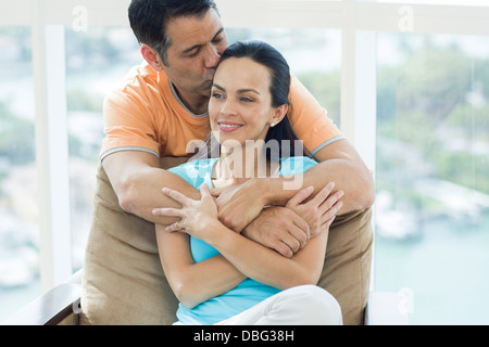 Hispanic couple hugging in armchair Stock Photo