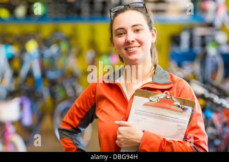 Caucasian woman with clipboard in bicycle shop Stock Photo