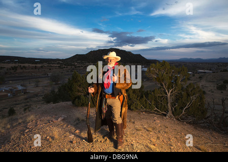 Caucasian man holding gun in dusty landscape Stock Photo