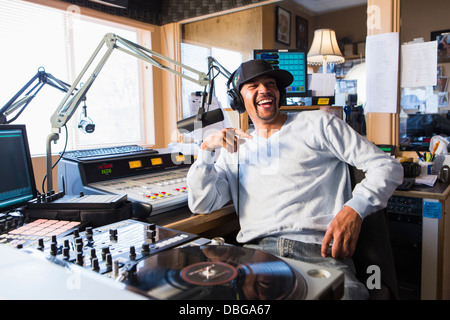 Mixed race disc jockey smiling in studio Stock Photo