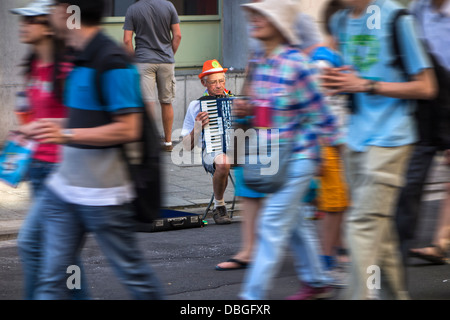 Sad scene of old man / accordionist playing accordion music unnoticed by pedestrians walking by in busy shopping street in city Stock Photo