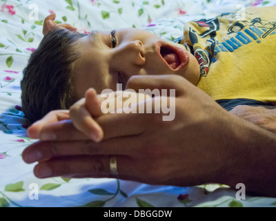 A young boy undergoes rigorous stretching exercises in physiotherapy. Stock Photo