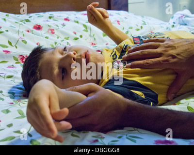 A young boy undergoes rigorous stretching exercises in physiotherapy. Stock Photo