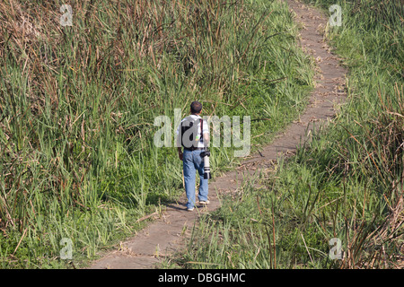 Man with a Canon camera and lens in greenery, here for bird watching. A small track inside the Okhla Bird Sanctuary in Noida. Stock Photo