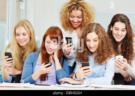 Many happy girls using social media with their smartphones in school Stock Photo