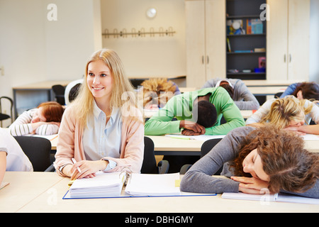 Students sleeping in school class and young woman keeping awake Stock Photo