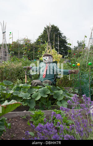 Seated scarecrow with jumper and tie in urban allotment Stock Photo
