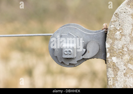 Wire fence tensioner ratchet device mounted on a concrete post and used to stretch and adjust the tension of the wire. Stock Photo