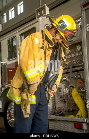 Wearing his helmet, a young firefighter dons his yellow safety jacket at a firehouse in Laguna Niguel, CA. Stock Photo