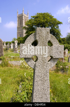old celtic cross with church and steeple in background Stock Photo