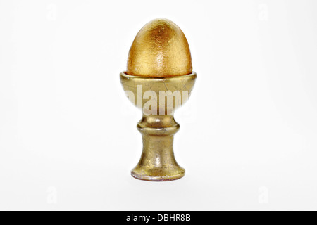 Hand painted gold egg in old egg cup on white background Stock Photo