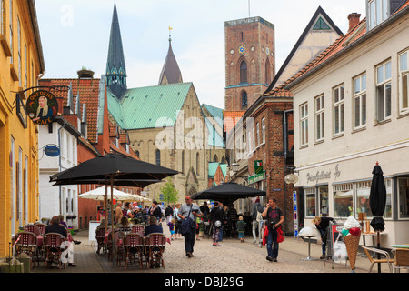 Outdoor cafes in pedestrianised cobbled main street in historic town with Our Lady Maria Cathedral beyond. Ribe Jutland Denmark