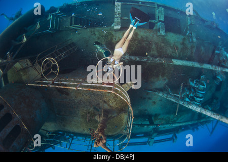 A woman blows bubble-rings while freediving (breah-hold diving) underwater on the side of the Kittiwake Shipwreck off Grand Caym Stock Photo