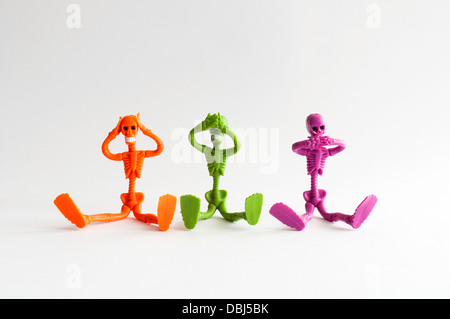 Three orange green and magenta skeletons pretending three wise monkeys Stock Photo