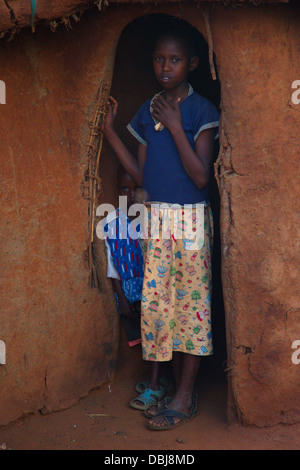 Two Masai children stand in the doorway of a traditional Masai dung hut. Ol Kinyei Conservancy area. Kenya, Africa. Stock Photo