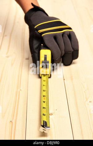 A worker measuring a block of wood using a measuring tool Stock Photo