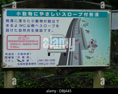 Sign in northern Okinawa warning drivers about slopes designed to help wildlife escape from drainage ditches. Stock Photo