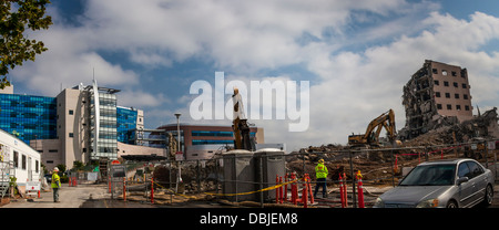 Left,  new Eden Medical Center, with construction crew and heavy equipment. Right, the old hospital, being demolished Stock Photo