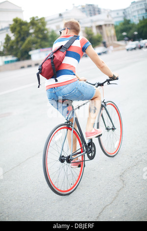 Back view of youngguy riding bicycle in the city center Stock Photo