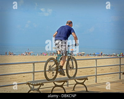 BIcycle stunt. A man riding his bike over a bench on the boardwalk in Brighton Beach Brooklyn, New York Stock Photo