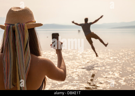 Croatia, Young woman on beach taking pictures Stock Photo