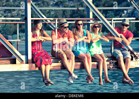 Croatia, Dalmatia, Young people sitting on footbridge, side by side Stock Photo
