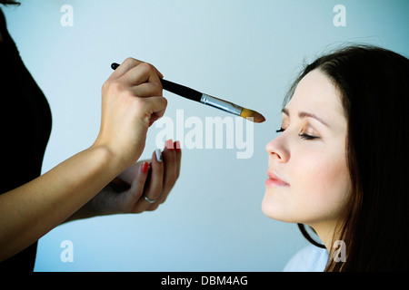 Stylist applying eyeshadow to young woman's face, Copenhagen, Denmark Stock Photo