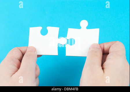 Two hands holding puzzle pieces and connecting them Stock Photo