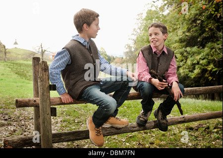 Two Boys Sitting On Wooden Fence, Bavaria, Germany, Europe Stock Photo