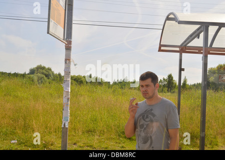 handsome young man smoking at a bus stop Stock Photo