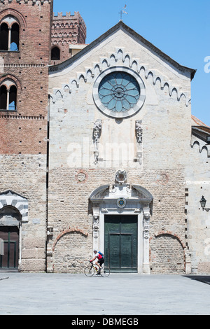 Cyclist riding past the cathedral of St Michael, Albenga, northern Italy Stock Photo