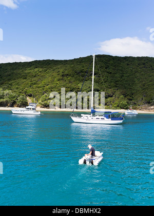 dh Urupukapuka Island anchorage BAY OF ISLANDS NEW ZEALAND Man in motor dinghy sailing and cruiser yachts anchored off shore yacht leisure Stock Photo