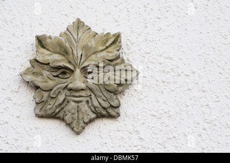 Green Man plaque on a white textured wall. Stock Photo