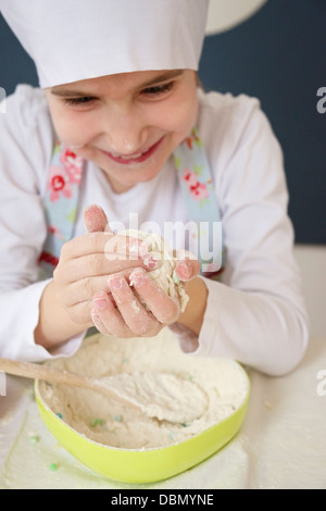Little girl with chef's hat kneading dough, Munich, Bavaria, Germany Stock Photo
