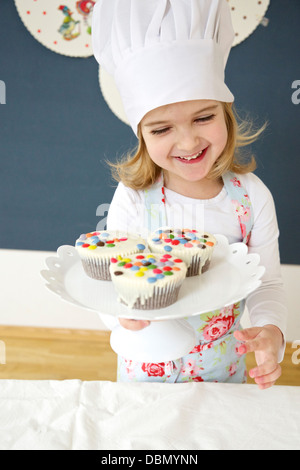 Little girl with chef's hat presenting muffins, Munich, Bavaria, Germany Stock Photo
