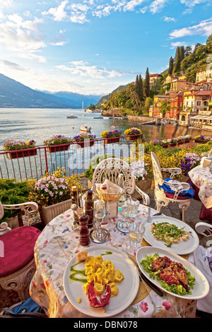 Romantic, beautiful dinner setting at Italian lake Como in the early evening. Three plates of Italian food are on a table Stock Photo