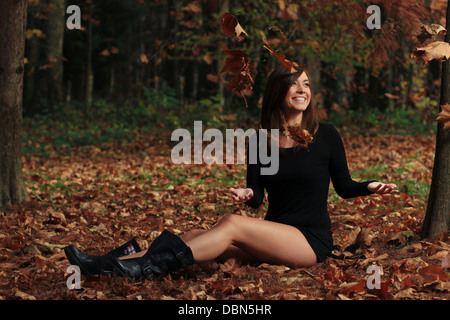 Young woman in forest throwing leaves in the air, Croatia, Europe Stock Photo