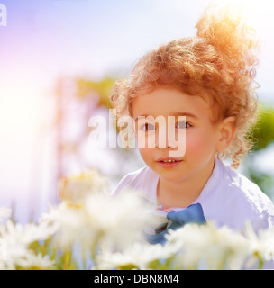 Closeup portrait of cute little boy on daisy field, having fun in beautiful park, summer holidays, recreation outdoors Stock Photo