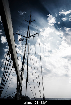 Mast of sailboat on dark cloudy sky background, storm in the sea, sailing sport, dramatic sunset, bad weather, water transport Stock Photo