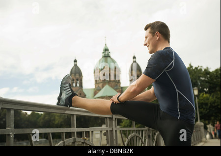 Young man stretching on bridge, Munich, Bavaria, Germany Stock Photo