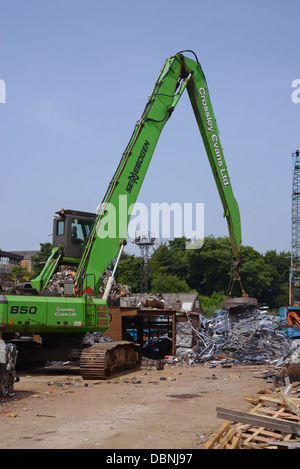 magnetic grab on crane lifting metal at scrapyard uk Stock Photo